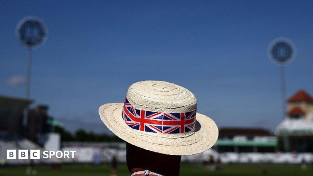 Toplotni talas u Velikoj Britaniji: Kako utiču sportovi, uključujući tenis, kriket i konjske trke? A man wearing a sun hat adorned with a Union Jack design watches on before a cricket match at Trent Bridge in Nottingham