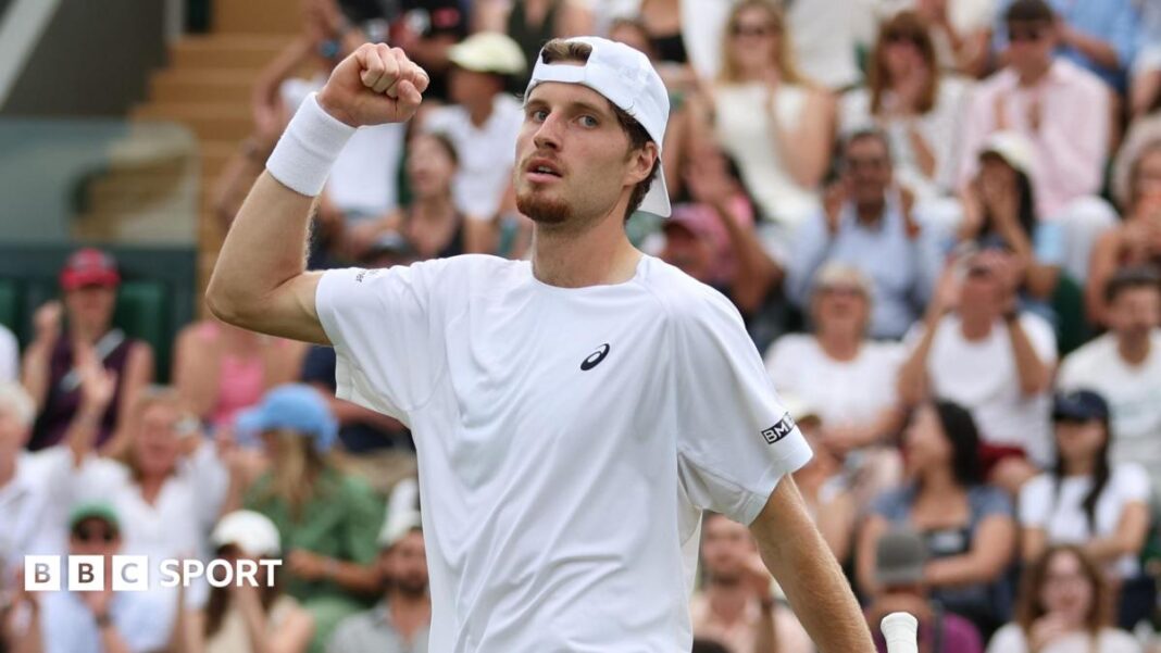 Toby Samuel: Britanac spreman da cilja prvih 100 na muškoj teniskoj rang listi Toby Samuel wearing a white tennis shirt and baseball cap backwards pumps his fist towards the sky
